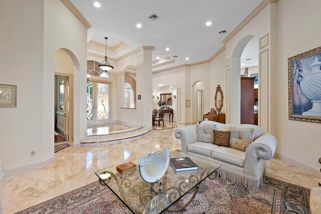 foyer entrance with crown molding, french doors, a raised ceiling, and a towering ceiling