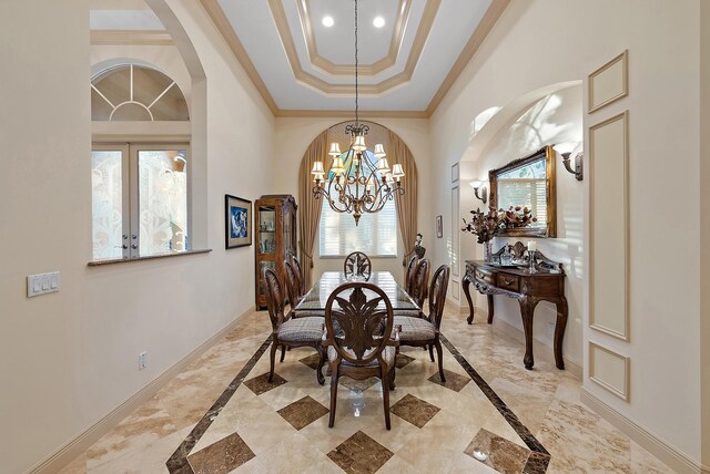 foyer entrance with a high ceiling, ornamental molding, a notable chandelier, and a tray ceiling