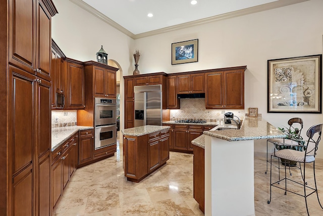 kitchen with sink, a kitchen breakfast bar, kitchen peninsula, a kitchen island, and stainless steel appliances