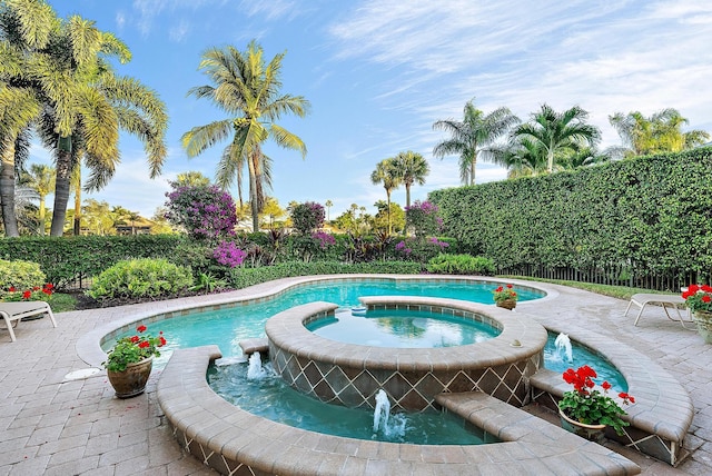 view of pool with a patio area, pool water feature, and an in ground hot tub