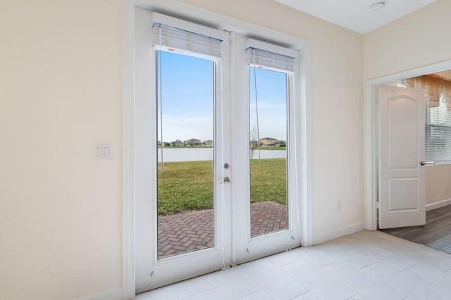 doorway with a water view, light tile patterned floors, and french doors