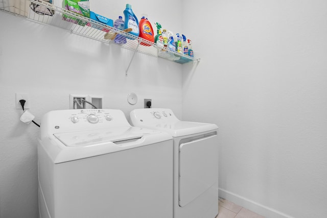 laundry area with light tile patterned floors and washing machine and clothes dryer