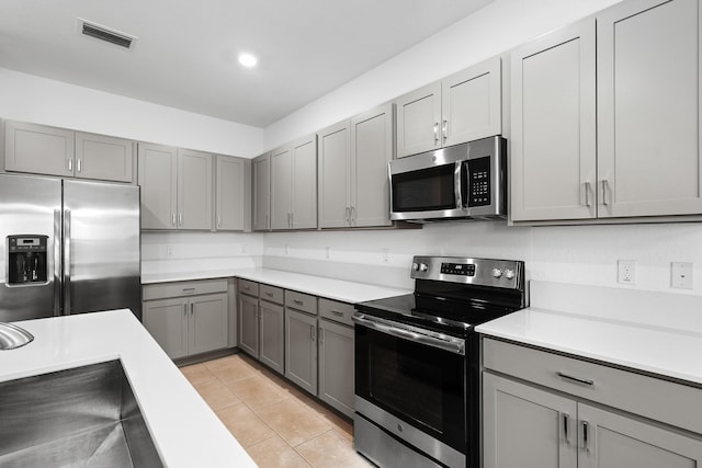 kitchen featuring gray cabinets, appliances with stainless steel finishes, and light tile patterned floors