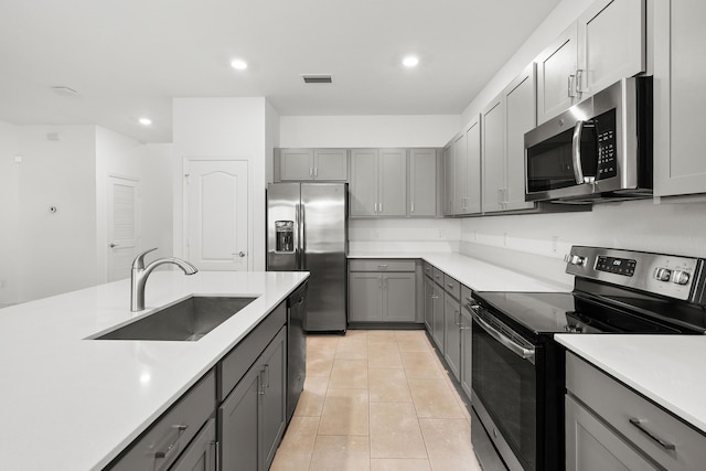 kitchen featuring sink, light tile patterned floors, gray cabinets, and appliances with stainless steel finishes