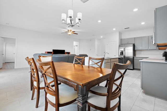 tiled dining room with sink and ceiling fan with notable chandelier