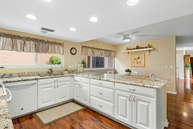 kitchen with sink, light stone counters, white dishwasher, kitchen peninsula, and white cabinets