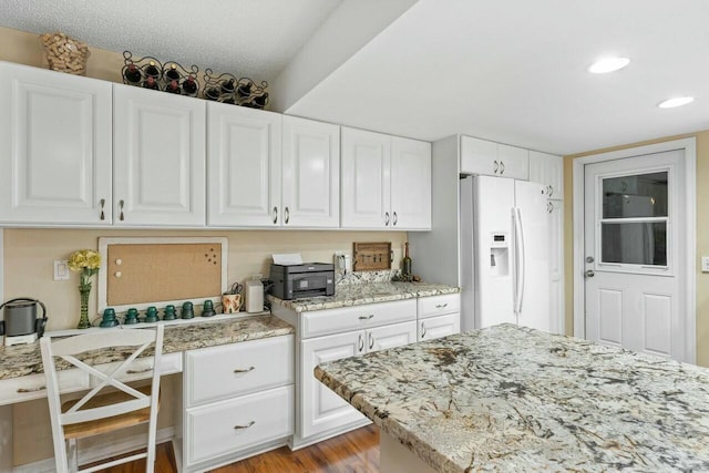 kitchen featuring white cabinetry, a textured ceiling, light wood-type flooring, light stone countertops, and white refrigerator with ice dispenser