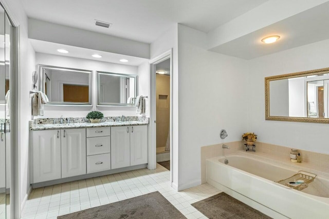 bathroom featuring vanity, a washtub, and tile patterned floors