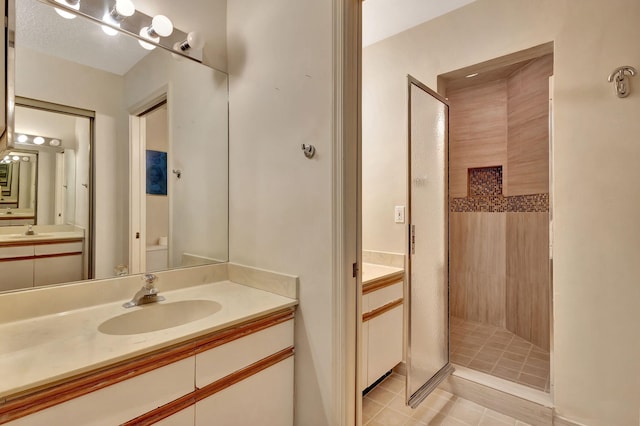 bathroom with a tile shower, vanity, and tile patterned floors