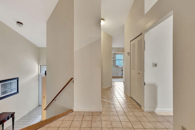 hall featuring light tile patterned floors and a textured ceiling