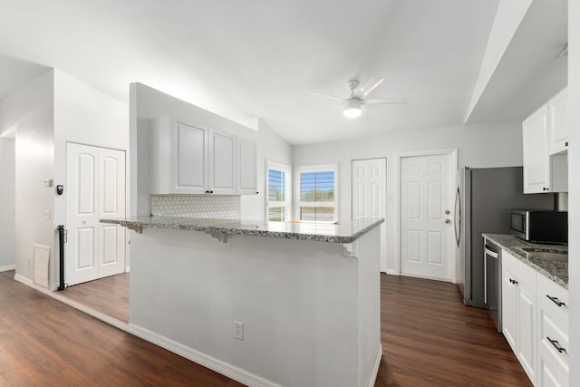 kitchen featuring stainless steel appliances, white cabinetry, light stone countertops, and a kitchen breakfast bar