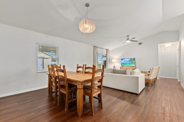 dining space with dark wood-type flooring, plenty of natural light, ceiling fan with notable chandelier, and vaulted ceiling