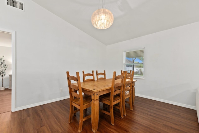 dining area featuring vaulted ceiling, dark wood-type flooring, and an inviting chandelier