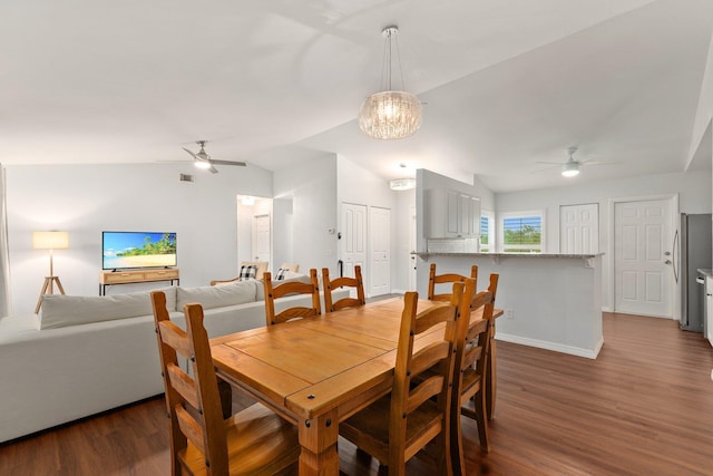 dining area featuring vaulted ceiling, ceiling fan with notable chandelier, and dark hardwood / wood-style floors