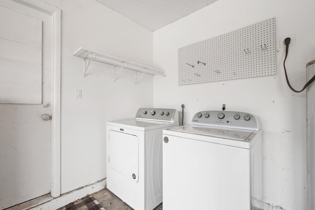 clothes washing area with separate washer and dryer and a textured ceiling