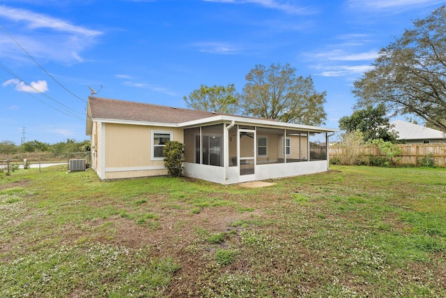 rear view of house featuring a yard, central AC unit, and a sunroom