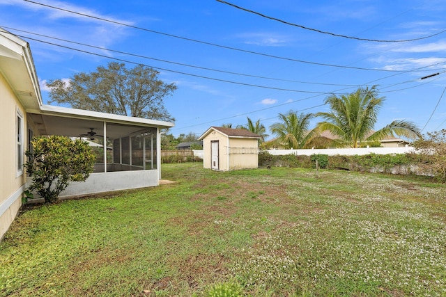 view of yard featuring ceiling fan, a sunroom, and a storage shed