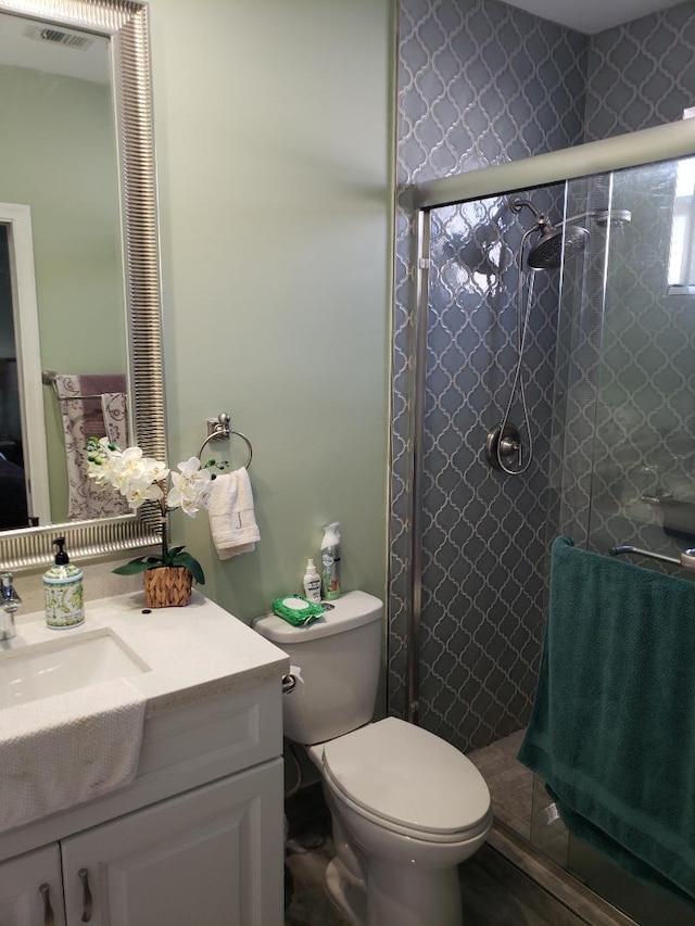 bathroom with vanity, toilet, and a shower with door