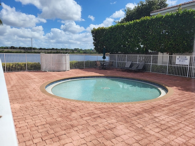 view of swimming pool with a water view and a patio area