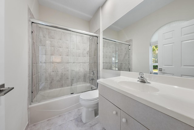 full bathroom featuring vanity, tile patterned floors, toilet, and combined bath / shower with glass door