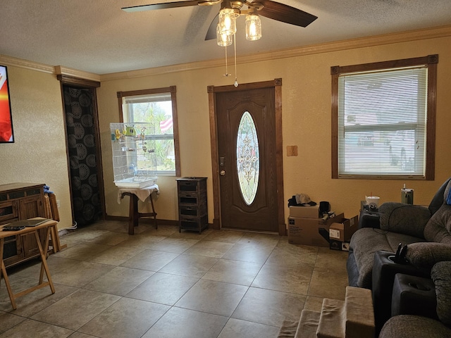 entryway with ornamental molding, tile patterned flooring, a textured ceiling, and a ceiling fan