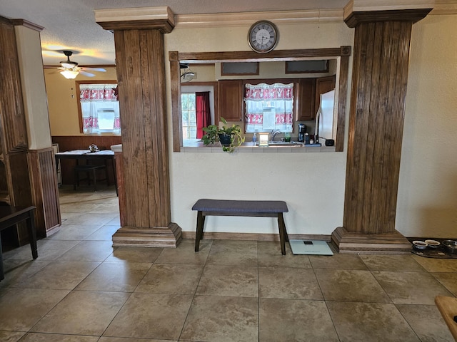 interior space featuring tile countertops, tile patterned flooring, freestanding refrigerator, and ornate columns