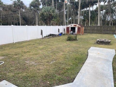 view of yard with an outdoor fire pit, a fenced backyard, and an outdoor structure