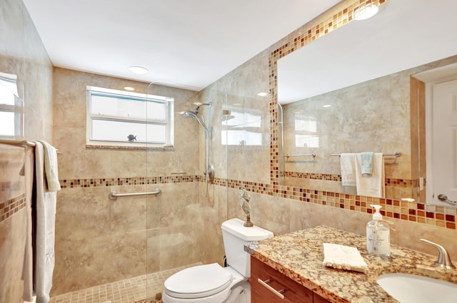 bathroom featuring tiled shower, toilet, vanity, and tile walls