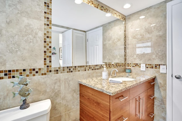 bathroom featuring tile walls, toilet, and vanity