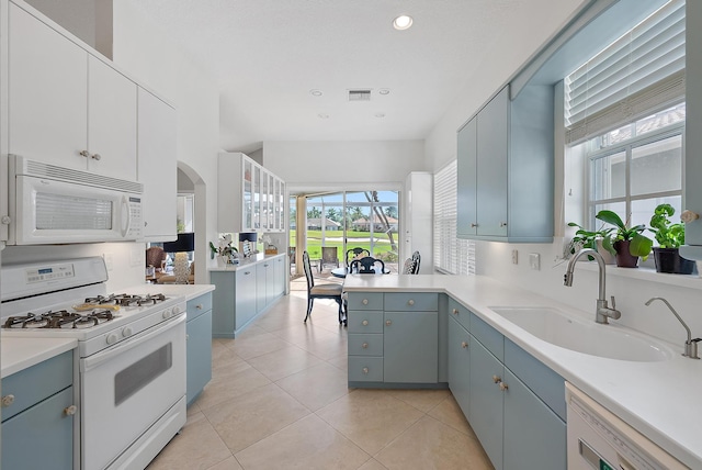 kitchen with sink, white appliances, light tile patterned floors, and kitchen peninsula