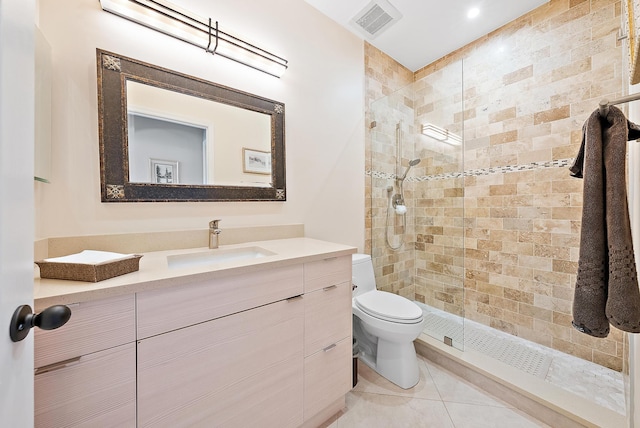 bathroom with tiled shower, vanity, toilet, and tile patterned flooring