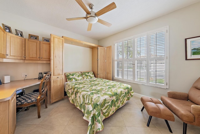 bedroom with light tile patterned flooring, ceiling fan, built in desk, and a textured ceiling