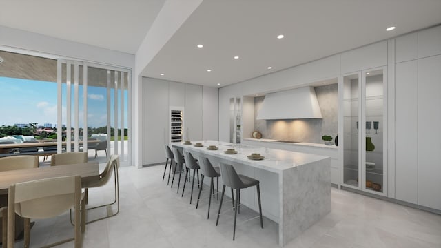 kitchen with wall chimney exhaust hood, backsplash, white cabinetry, black electric stovetop, and light stone counters