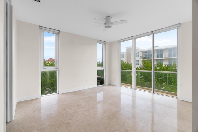 unfurnished room featuring ceiling fan and a wall of windows