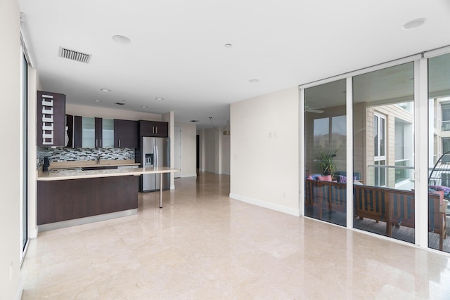 kitchen with dark brown cabinetry, backsplash, a wealth of natural light, and stainless steel fridge