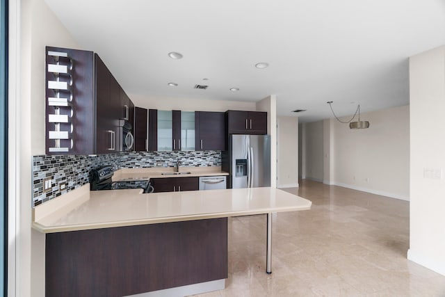 kitchen with appliances with stainless steel finishes, a breakfast bar area, backsplash, kitchen peninsula, and dark brown cabinets