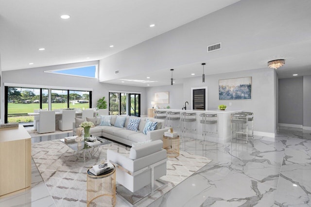 living area with baseboards, visible vents, marble finish floor, recessed lighting, and high vaulted ceiling