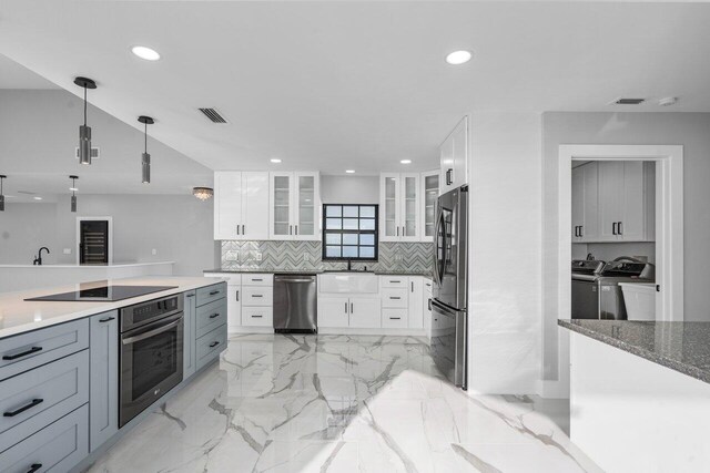 kitchen featuring white cabinetry, dark stone counters, vaulted ceiling, and tasteful backsplash