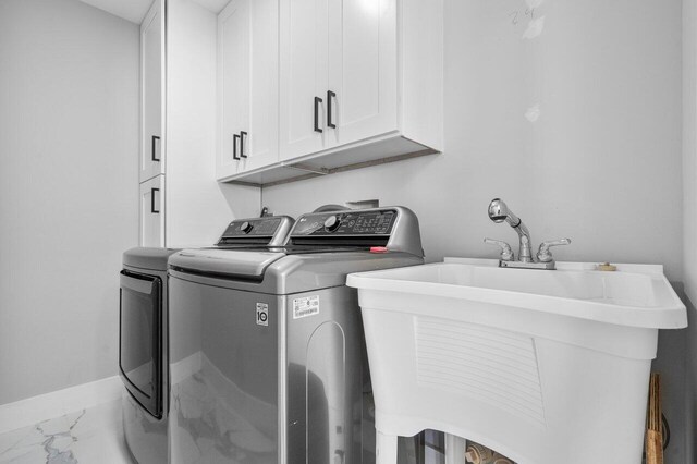 laundry area with separate washer and dryer, cabinet space, baseboards, marble finish floor, and a sink