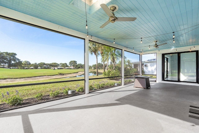 unfurnished sunroom featuring a water view, track lighting, plenty of natural light, and ceiling fan