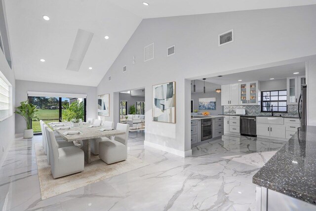 51 Woods Ln, Boynton Beach, FL 33436 - dining area with light marble finish flooring, high vaulted ceiling, a skylight, and recessed lighting