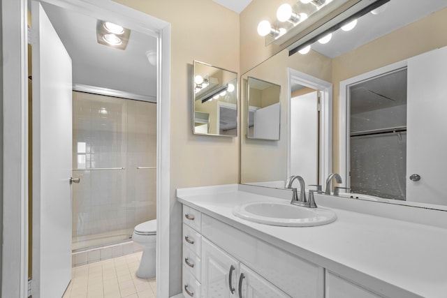 bathroom with a shower with door, vanity, tile patterned floors, and toilet