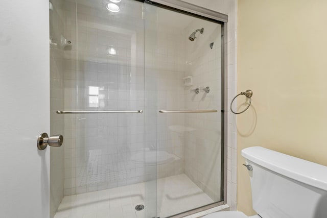 bathroom featuring toilet and a shower with shower door