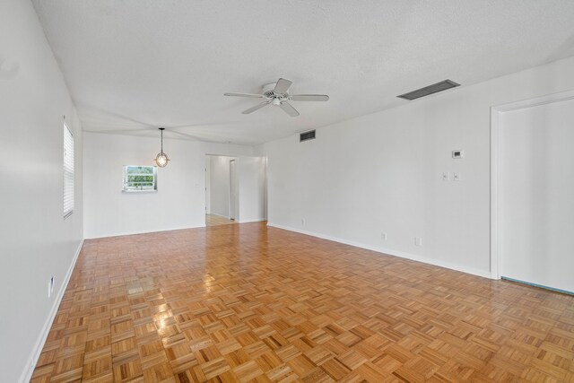 carpeted empty room featuring ceiling fan and a textured ceiling