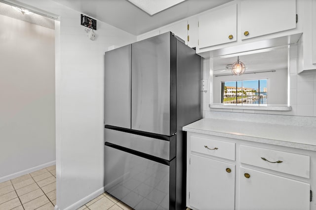 kitchen featuring light tile patterned flooring, backsplash, stainless steel fridge, and white cabinets