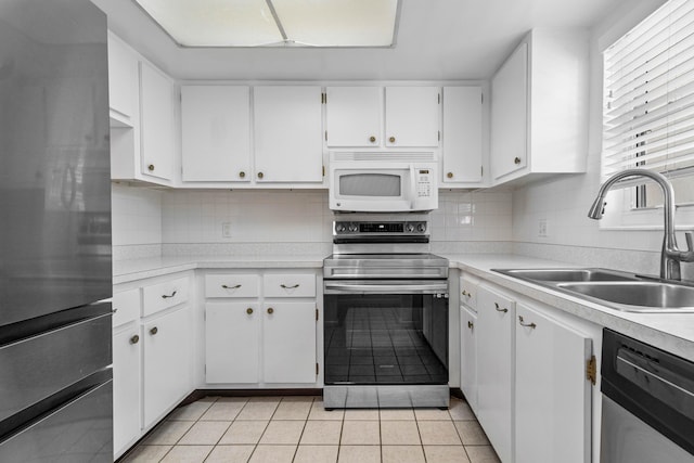 kitchen with sink, light tile patterned floors, appliances with stainless steel finishes, white cabinetry, and tasteful backsplash