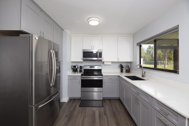 kitchen with dark wood-type flooring, appliances with stainless steel finishes, gray cabinets, and sink