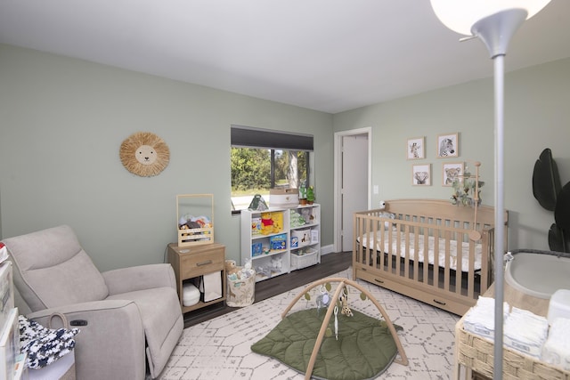 bedroom with wood-type flooring and a nursery area