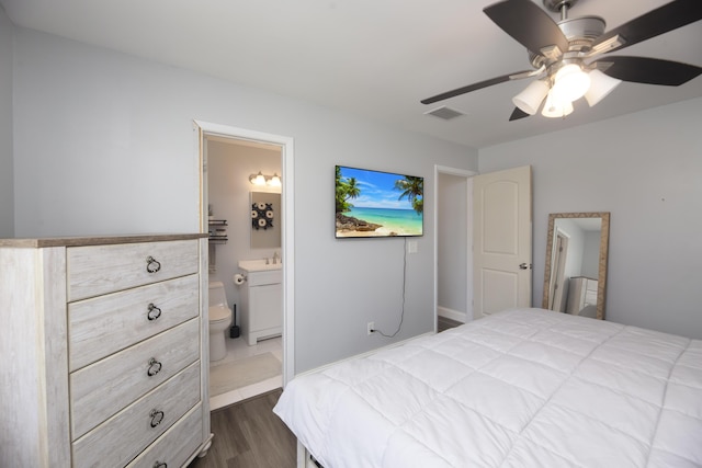 bedroom with ceiling fan, connected bathroom, and dark hardwood / wood-style flooring