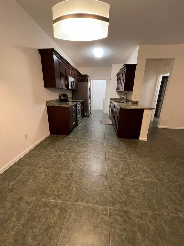 kitchen with dark tile patterned flooring, sink, dark brown cabinetry, and appliances with stainless steel finishes